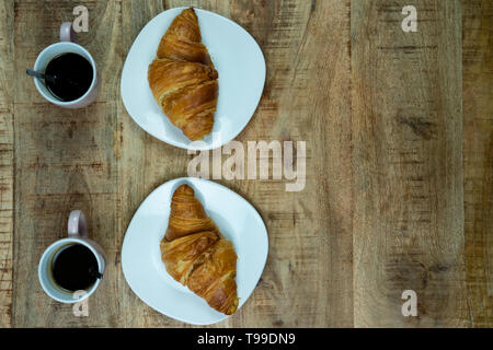 Le petit-déjeuner ou déjeuner pour deux. Des croissants fraîchement cuits sur une plaque avec du café. Sur un fond de bois, vue du dessus Banque D'Images