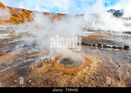 Une fumerolle avec traînée de vapeur dans le champ de Geysers Tatio au lever du soleil, Désert d'Atacama, au Chili. Banque D'Images