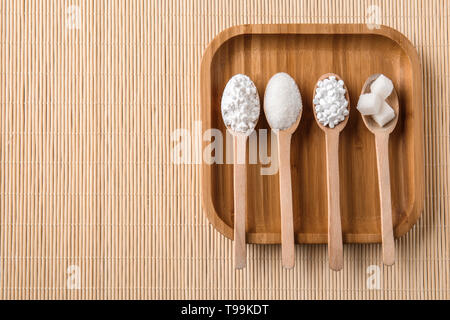 Les cuillères avec différents types de sucre sur le plateau en bois Banque D'Images