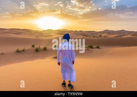 Homme portant des vêtements traditionnels berbères dans le désert du Sahara à l'aube, Maroc Banque D'Images