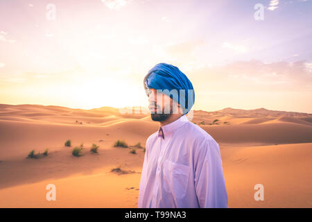 Homme portant des vêtements traditionnels berbères dans le désert du Sahara à l'aube, Maroc Banque D'Images