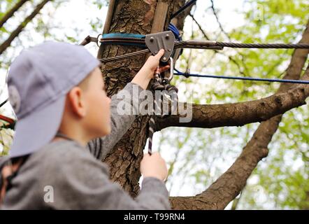 Garçon d'âge préscolaire des enfants est un obstacle à la sécurité d'un équipement d'alpinisme Cours corde haute Banque D'Images