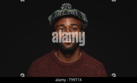 Portrait d'un homme en chapeau écossais sur fond noir. African American man en vêtements de laine looking at camera. Banque D'Images