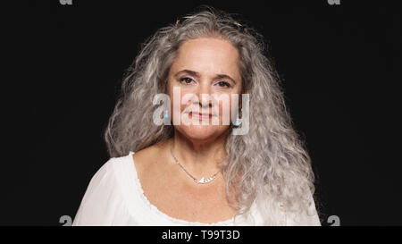 Vieille femme au cheveux blanc isolé sur fond noir. Close up of senior woman looking at camera. Banque D'Images