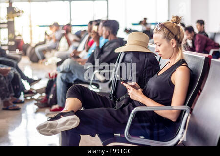 Female traveler talking on cell phone en attendant de monter à bord d'un avion à l'embarquement au terminal de l'aéroport d'Asie. Banque D'Images