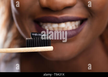 Close-up of Young Woman Holding brosse à dents avec dentifrice noir charbon actif Banque D'Images