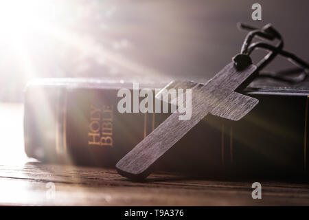 Croix chrétienne en bois sur la Sainte Bible sur table en bois Banque D'Images