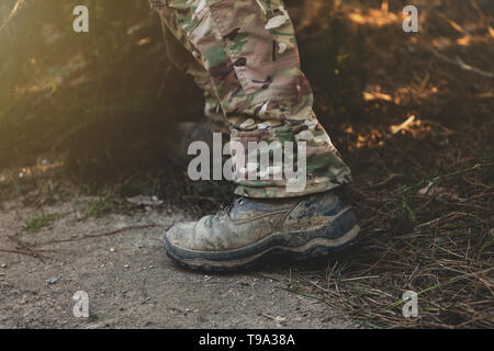 Brown bottes militaires sur la boue et les flaques. Banque D'Images