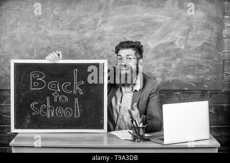 Enseignant ou directeur d'école accueille avec tableau noir inscription retour à l'école. Bienvenue à nouveau. Enseignant accueille de nouveaux élèves à entrer dans l'établissement d'enseignement. Début de nouvelle année scolaire en septembre. Banque D'Images