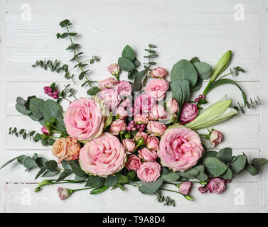 Belles roses roses avec des branches d'eucalyptus sur fond de bois blanc Banque D'Images