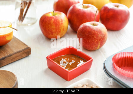 Des pommes mûres et le bol de sauce sur tableau blanc Banque D'Images