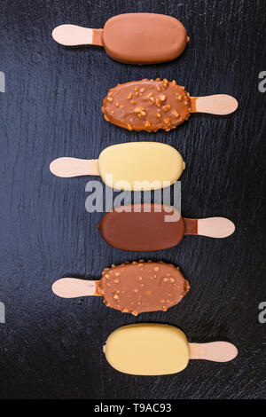 Ice cream on stick couverts de chocolat sur l'ardoise noire. Banque D'Images