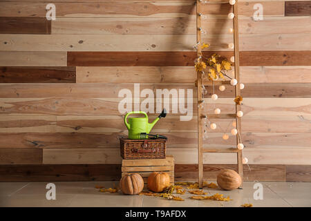 Belle composition d'automne avec des citrouilles, arrosoir et escabeau près de mur en bois Banque D'Images