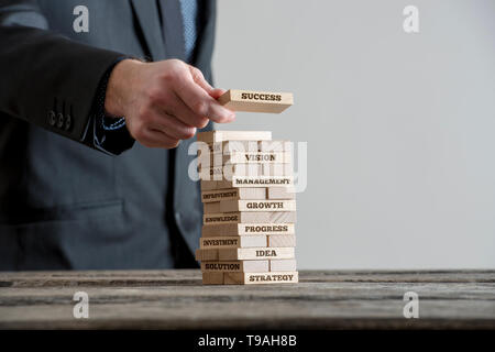 Woman in Black suite construire tour de briques domino en bois avec des signes de motivation concept a propos de l'entreprise gouvernementale. Close-up o Banque D'Images