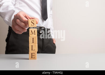 Empilage de cubes en bois d'affaires avec des lettres sur eux pour épeler le mot sourire dans une image conceptuelle de la relation d'affaires. Banque D'Images