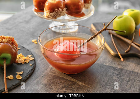 Apple en bol en verre avec le caramel sur table gris Banque D'Images