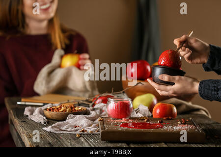 Femme trempant dans un bol d'apple avec le caramel sur table en bois Banque D'Images