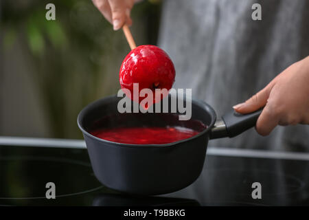 Femme plongeant dans la casserole avec le caramel apple Banque D'Images