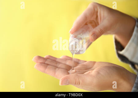 Femme à l'aide de gel antibactérien pour les mains sur un fond de couleur, gros plan Banque D'Images