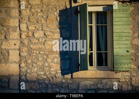 Vue sur fenêtre dans maison médiévale en Provence dans les feux du soleil au lever du soleil, au sud de la France Banque D'Images