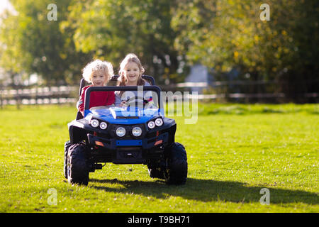 Petite voiture électrique de conduite pour les enfants en été. Jouets de plein air. Les enfants dans l'alimentation de la batterie du véhicule. Little Boy and girl riding camion jouet dans le jardin. Fam Banque D'Images