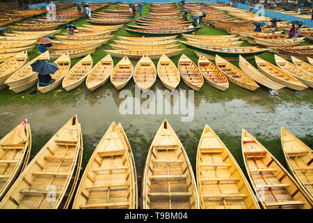 Des centaines de petits bateaux en bois vu affiché pour la vente à un marché que les sections locales à se préparer à la saison de la mousson. Des dizaines troupeau de loin pour acheter leur propre bateau à un marché en Manikganj, Bangladesh, de façon à être prête pour les inondations qui peuvent survenir à tout moment. Après de fortes pluies, il est courant que les berges des rivières pour éclater, submerger les villes et villages. Cela signifie que les voitures et les bus devenus superflus et les gens sont obligés de voyager par bateau. Chacun des bateaux en bois et avirons sont fait à la main par des artisans locaux et peut être acheté pour aussi peu que 1700 Taka bangladais - l'équivalent de 20 US dollar. Banque D'Images