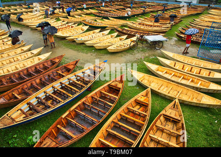 Des centaines de petits bateaux en bois vu affiché pour la vente à un marché que les sections locales à se préparer à la saison de la mousson. Des dizaines troupeau de loin pour acheter leur propre bateau à un marché en Manikganj, Bangladesh, de façon à être prête pour les inondations qui peuvent survenir à tout moment. Après de fortes pluies, il est courant que les berges des rivières pour éclater, submerger les villes et villages. Cela signifie que les voitures et les bus devenus superflus et les gens sont obligés de voyager par bateau. Chacun des bateaux en bois et avirons sont fait à la main par des artisans locaux et peut être acheté pour aussi peu que 1700 Taka bangladais - l'équivalent de 20 US dollar. Banque D'Images