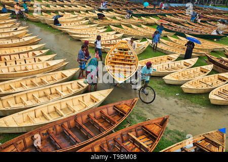 Des centaines de petits bateaux en bois vu affiché pour la vente à un marché que les sections locales à se préparer à la saison de la mousson. Des dizaines troupeau de loin pour acheter leur propre bateau à un marché en Manikganj, Bangladesh, de façon à être prête pour les inondations qui peuvent survenir à tout moment. Après de fortes pluies, il est courant que les berges des rivières pour éclater, submerger les villes et villages. Cela signifie que les voitures et les bus devenus superflus et les gens sont obligés de voyager par bateau. Chacun des bateaux en bois et avirons sont fait à la main par des artisans locaux et peut être acheté pour aussi peu que 1700 Taka bangladais - l'équivalent de 20 US dollar. Banque D'Images