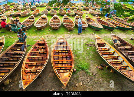 Des centaines de petits bateaux en bois vu affiché pour la vente à un marché que les sections locales à se préparer à la saison de la mousson. Des dizaines troupeau de loin pour acheter leur propre bateau à un marché en Manikganj, Bangladesh, de façon à être prête pour les inondations qui peuvent survenir à tout moment. Après de fortes pluies, il est courant que les berges des rivières pour éclater, submerger les villes et villages. Cela signifie que les voitures et les bus devenus superflus et les gens sont obligés de voyager par bateau. Chacun des bateaux en bois et avirons sont fait à la main par des artisans locaux et peut être acheté pour aussi peu que 1700 Taka bangladais - l'équivalent de 20 US dollar. Banque D'Images