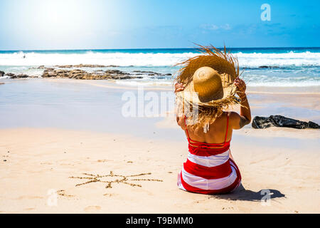 Des vacances d'été vacances à la mer, au paradis belle station personnes concept avec belle femme avec chapeau de tourisme vu de l'arrière bénéficiant d'un le sable Banque D'Images