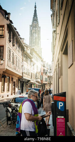 Strasbourg, France - Jul 22, 2017 : l'homme de payer pour le stationnement à cetral Strasbourg au parcmètre avec la cathédrale Notre-Dame en arrière-plan et de shopping sur la Rue des Juifs Banque D'Images