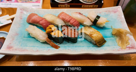 Plateau de une variété de sushis nigiri et rouleaux de sushi (sushi gunkan) avec des algues, et de gingembre mariné (gari) sur le côté du restaurant au Japon. Banque D'Images