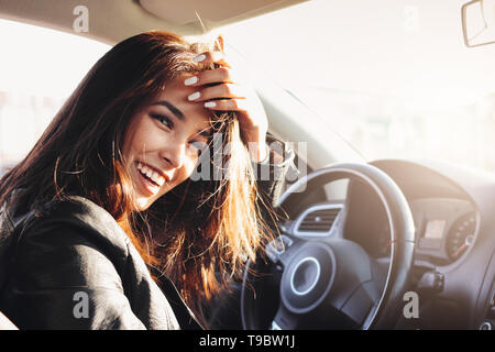 Portrait de la belle brune cheveux longs happy young asian woman driving la voiture voyageurs Banque D'Images