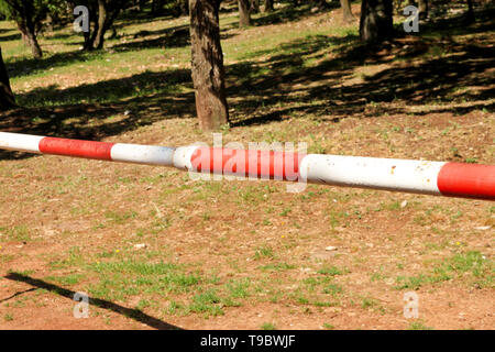 Panneau d'avertissement rouge et blanc sur l'herbe verte de barrière dans la nature. Transport, réglementation de la circulation. Vieille clôture faite et blanc et rouge dans la rue Banque D'Images