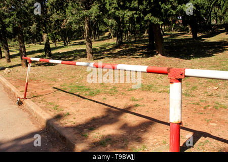 Panneau d'avertissement rouge et blanc sur l'herbe verte de barrière dans la nature. Transport, réglementation de la circulation. Vieille clôture faite et blanc et rouge dans la rue Banque D'Images