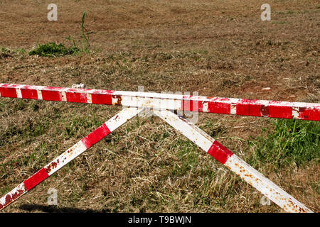 Panneau d'avertissement rouge et blanc sur l'herbe verte de barrière dans la nature. Transport, réglementation de la circulation. Vieille clôture faite et blanc et rouge dans la rue Banque D'Images