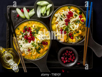 Laksa avec citrouille et lait de coco, riz nouilles, de brocoli et de graines de grenade en portions plaques noires sur un fond sombre. plat végétalien sain Banque D'Images