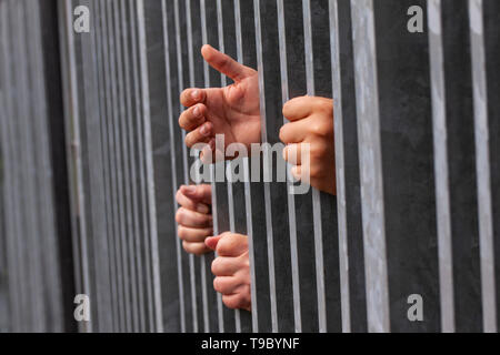 Mains tenant et faisant preuve de solides barres de fer. Prison ou crise d'immigrants et de réfugiés. Clôture frontalière ou concept spectaculaire Banque D'Images