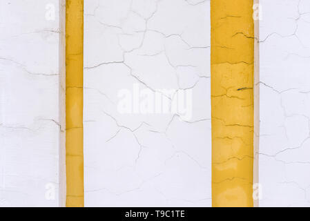 Le mur d'un bâtiment ancien. Les lignes jaunes et blanches. Fissure sur le mur. Surface de ciment fissurés. La conception et l'architecture. Banque D'Images