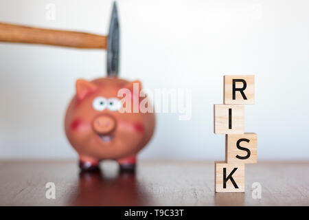 Main tenant un marteau au-dessus une tirelire et des risques sur les cubes en bois écrit word Banque D'Images