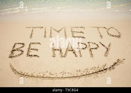 Close-up de temps d'être heureux et sourire texte écrit sur Sand At Beach Banque D'Images