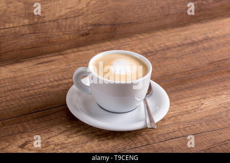 Tasse de blancs aromatiques délicieux cappuccino fraîchement préparé avec généreuse portion de crème douce sur une table en bois rustique. Banque D'Images