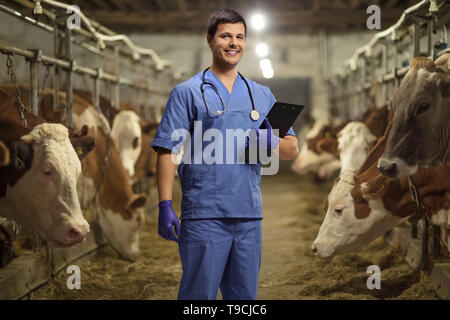 Jeune homme avec un vétérinaire presse-papiers sur une ferme de vache Banque D'Images