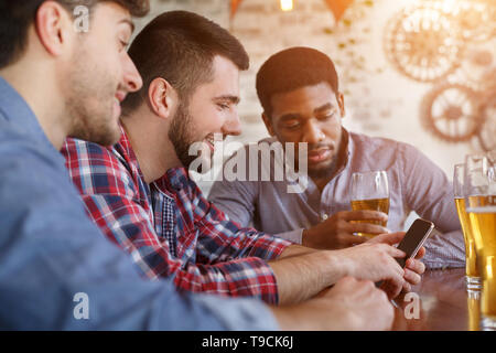 Réunion d'amis. Man Showing Photos sur smartphone Banque D'Images