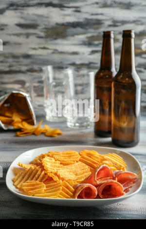 La plaque avec les chips de pomme de terre croustillante, du bacon et de la bière sur la table en bois Banque D'Images