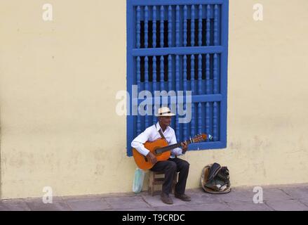 Cuba Personnes âgées homme assis et en jouant de la guitare instrument sur les rues pavées de la vieille ville de Trinidad, Cuba près de Plaza Mayor Banque D'Images