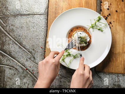 Woman eating tasty tartare de hareng avec œuf poché sur tableau Banque D'Images