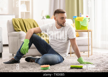 Jeune homme se reposant après le nettoyage de son appartement Banque D'Images