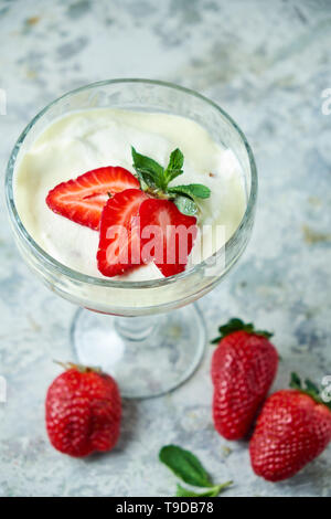 La crème glacée avec des fraises dans un vase de verre. Fond texturé gris. Le Dessert. La chaîne alimentaire Banque D'Images
