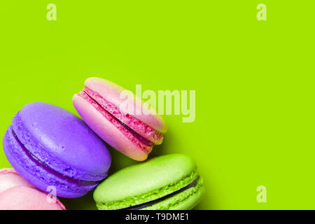 Libre de macarons sucrés colorés sur fond vert avec copie espace, vue du dessus. Pour dessert français servi avec un thé ou café Banque D'Images
